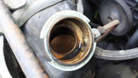 1984 Ford Bronco - Close-up of a vehicle's radiator cap opening, showing signs of corrosion and fluid.