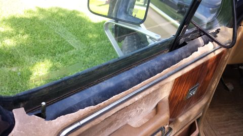 1984 Ford Bronco - Interior view of a 1984 Ford Bronco door panel showing wood grain trim and chrome accents.