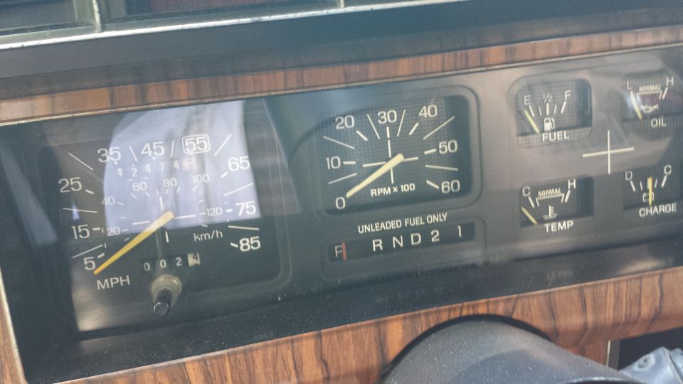 Dashboard with speedometer, tachometer, fuel, oil, temp, and charge gauges. Wood grain trim visible
