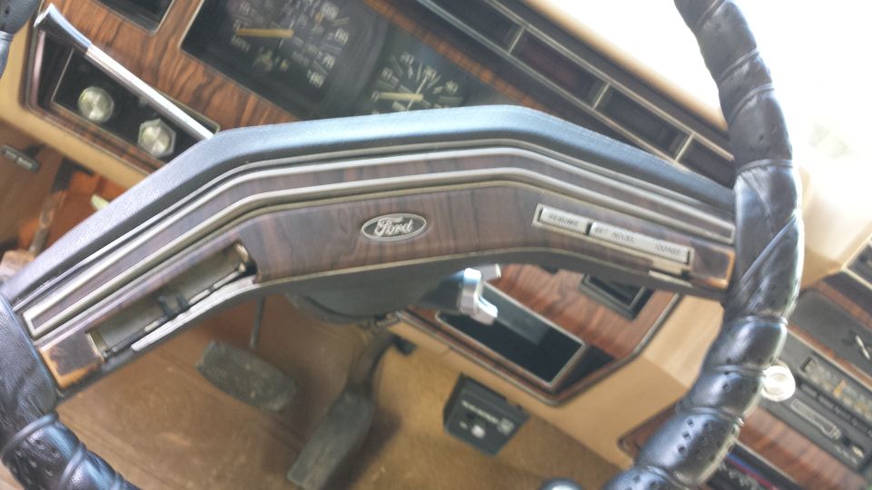 1980 Ford Bronco interior dashboard with wood grain trim and a Ford logo on the steering wheel