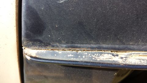 1984 Ford Bronco - A close-up view shows the seam between two body panels on a vehicle, revealing signs of wear and corrosion.