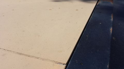 1984 Ford Bronco - Close-up view of the seam between a tan and dark blue car hood.