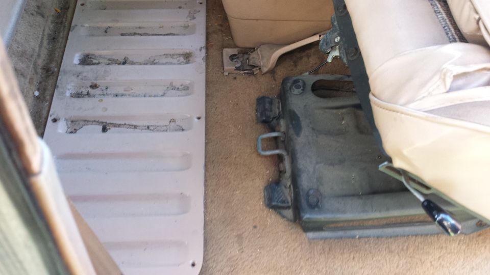 Interior view of vehicle floor with a ribbed metal panel and seat mounting hardware