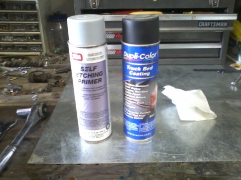 1978 Ford Bronco - A can of self-etching primer and a can of truck bed coating are displayed in a workshop setting.