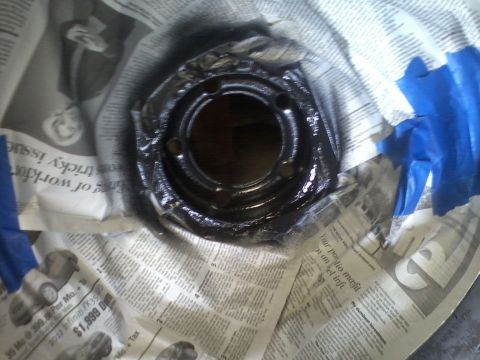 1978 Ford Bronco - A wheel hub is being prepped for painting, covered with newspaper and secured with blue painter's tape.