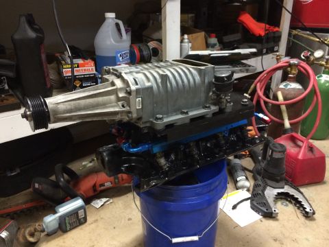 1996 Ford Bronco - A supercharger assembly is shown resting on a blue bucket in a workshop setting.