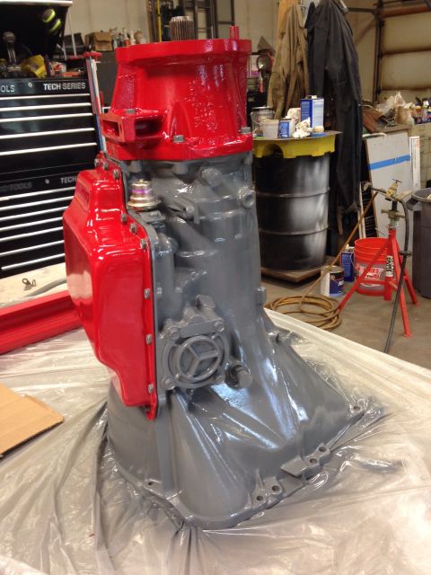 1993 Ford Bronco - Rebuilt transmission assembly, painted gray and red, sits on plastic sheeting in a workshop environment.