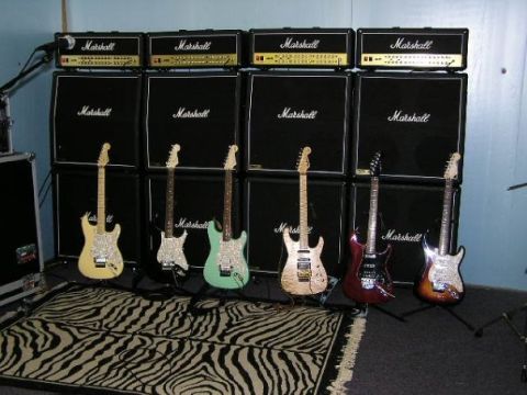 1994 Ford Bronco - A collection of electric guitars stands before a wall of Marshall amplifiers, arranged on a zebra-patterned rug.