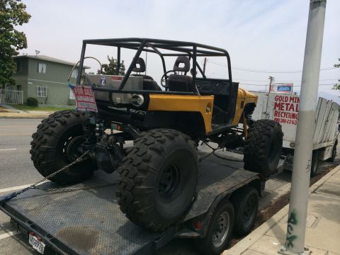 1968 Ford Mustang - A heavily modified yellow off-road vehicle with oversized tires is being transported on a trailer, displaying a "FOR SALE" sign.
