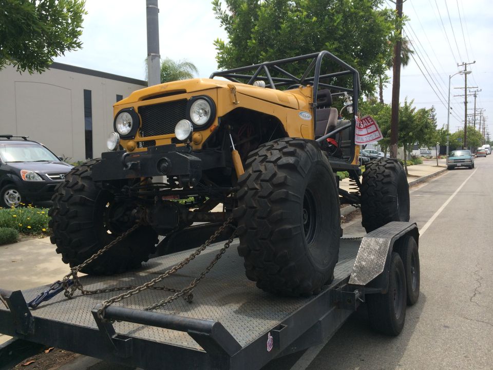 Yellow off-road vehicle with large tires on a trailer, front view