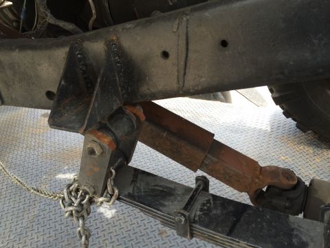 1968 Ford Mustang - The underside of a vehicle shows a rusty driveshaft connected to the leaf spring and frame, with a chain secured to the suspension.
