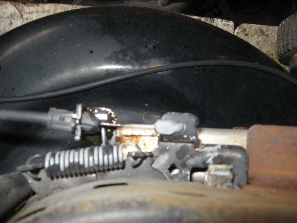 Throttle cable mechanism with spring and metal bracket, close-up view