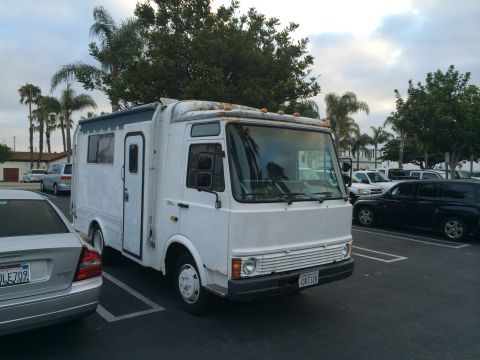 1968 Ford Mustang - This white RV motorhome is parked in a lot, with other vehicles visible in the background.