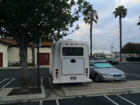 1968 Ford Mustang - A white RV and a silver sedan are parked in a lot near palm trees and a marina.