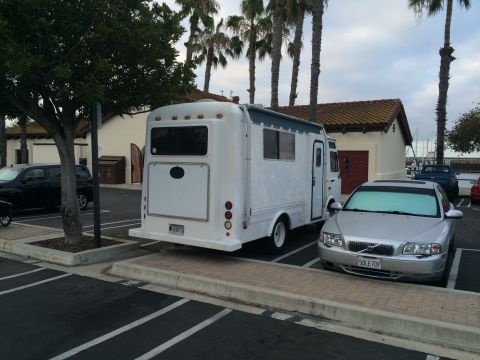 1968 Ford Mustang - A white RV is parked in a lot next to a silver Volvo sedan, with palm trees in the background.