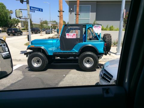 1968 Ford Mustang - Blue Jeep CJ-7 with shark decal and 'FOR SALE' signs is parked on a street corner.
