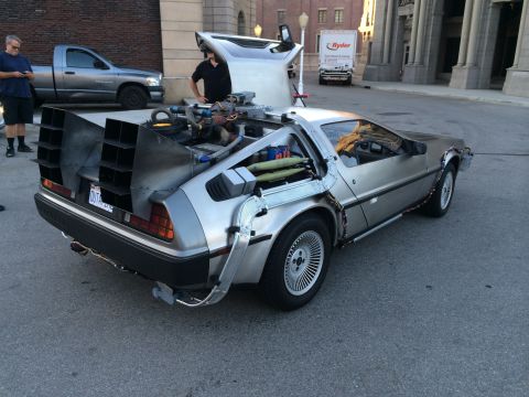 1968 Ford Mustang - Silver DeLorean DMC-12 with flux capacitor and vents is parked on a street.
