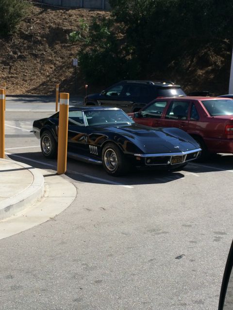 1968 Ford Mustang - A black 1969 Chevrolet Corvette is parked next to other vehicles.