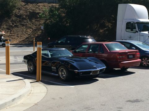 1968 Ford Mustang - A black 1969 Chevrolet Corvette Stingray is parked in a lot with other vehicles.