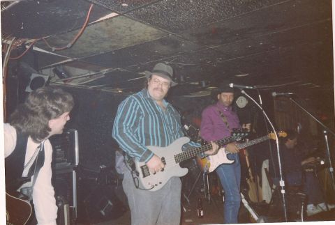 1994 Ford Bronco - Musicians play guitars and bass on a dimly lit stage during a live performance.