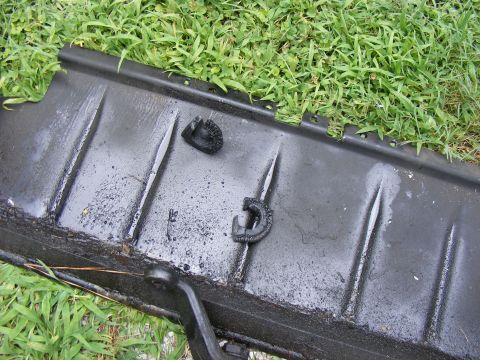 Black oil pan with two rubber grommets on grass. Supermotors.net logo visible