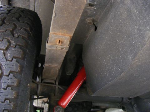Rear leaf spring and red shock absorber on vehicle undercarriage