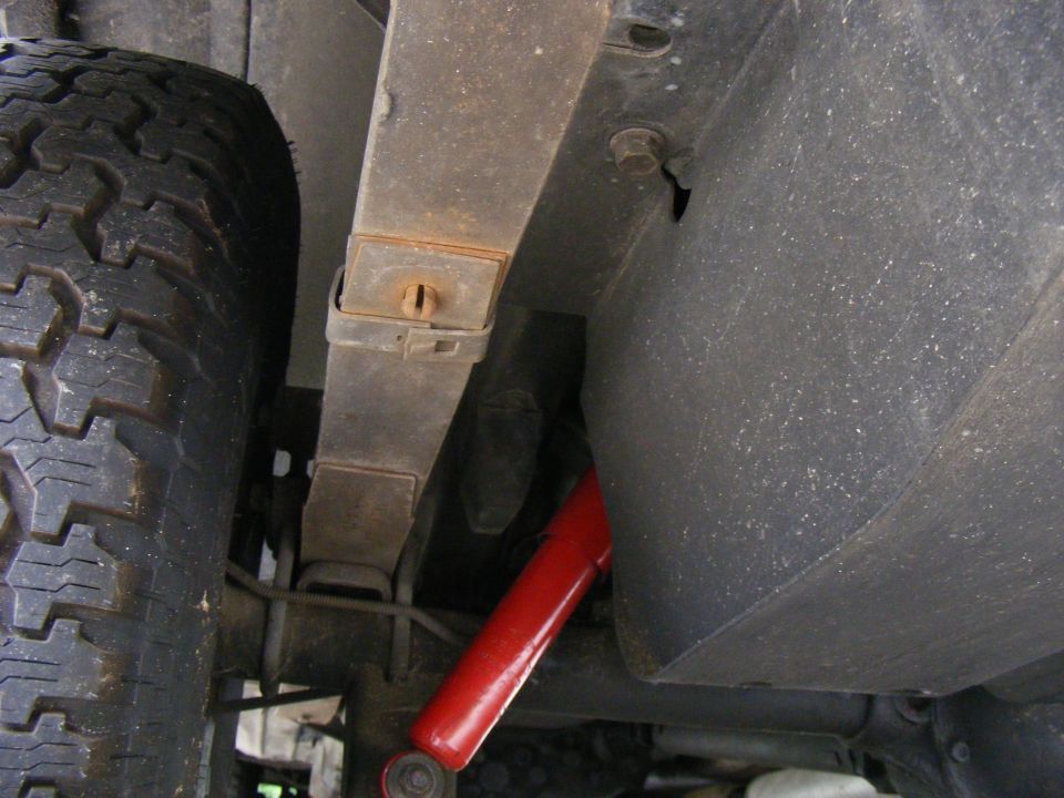 Rear leaf spring and red shock absorber on vehicle undercarriage