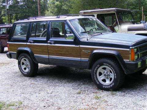 Wood-paneled Jeep Grand Wagoneer parked next to another SUV