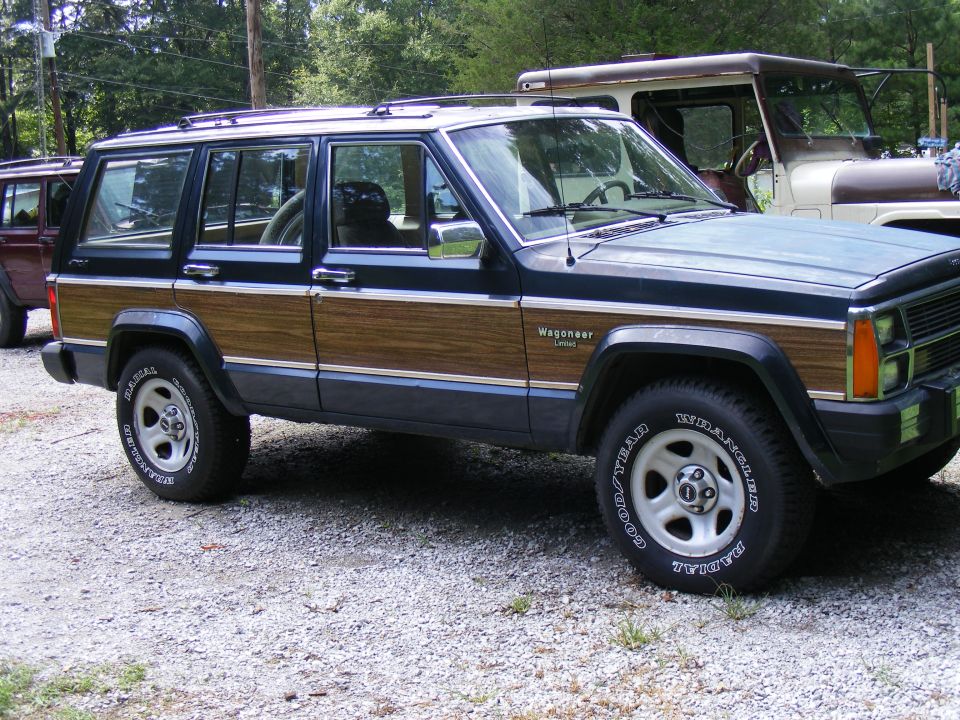 Wood-paneled Jeep Grand Wagoneer parked next to another SUV