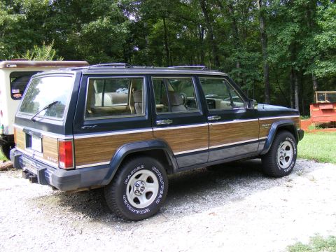 Dark blue Jeep Cherokee with wood paneling, rear 3/4 view