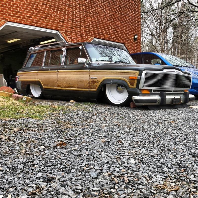 Wood-paneled station wagon, lowered, parked in front of a garage. Another car is visible behind it