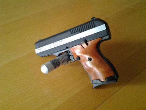 2003 Ford Crown Victoria - A pistol with a rolled-up dollar bill in its chamber rests on a wooden surface.