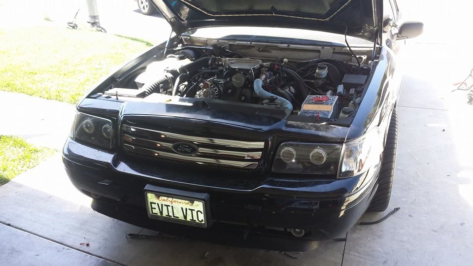 Black Ford sedan with hood open and EVIL VIC plate