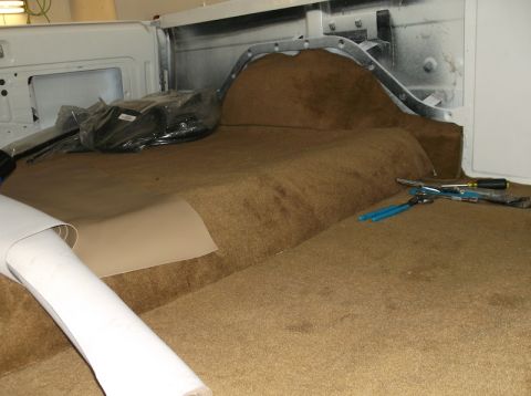 1979 Ford Bronco - The interior of a 1979 Ford Bronco shows new carpet installation in progress, with tools and materials laid out.