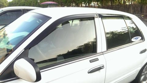 2000 Mercury Grand Marquis - A white 2000 Mercury Grand Marquis is parked next to another vehicle, showing its side profile and door keypad.