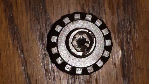 1984 Ford Bronco - Close-up of a metal cap with a hex bolt and a distinctive serrated outer edge.
