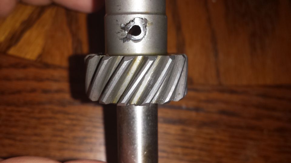 metal gear with helical teeth and a damaged hole above it