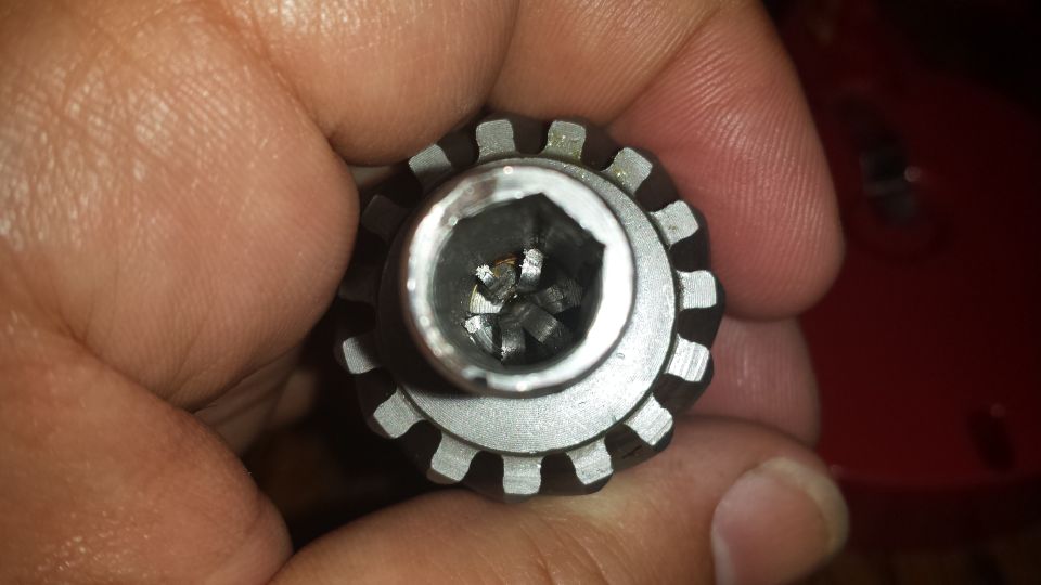 Close-up of a hand holding a splined socket tool with a hexagonal opening