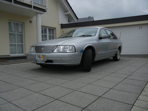 1999 Ford Fairlane - Silver 1999 Ford Fairlane sedan parked on a paved driveway in front of a residential building.