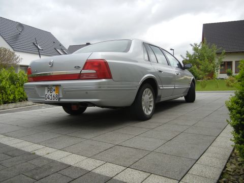 1999 Ford Fairlane - This silver sedan, likely a Ford sedan from the early 2000s, is shown from the rear on a cloudy day.