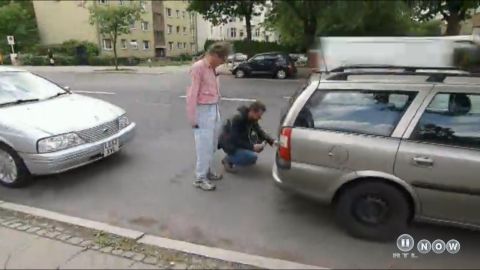 1999 Ford Fairlane - Two men are working on the rear of a silver station wagon parked on a street.
