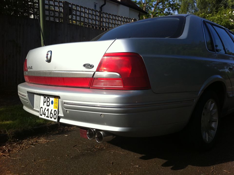 Rear view of silver Ford sedan with a red stripe on the trunk and dual exhaust pipes