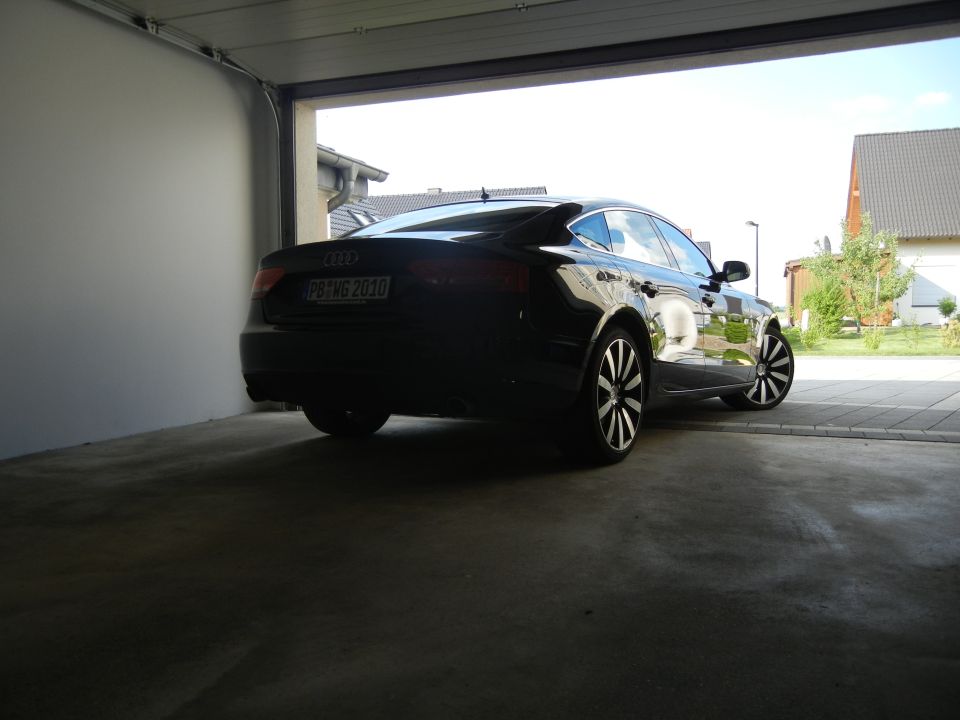 Black Audi sedan parked in a garage, rear view. License plate reads PB-WG 2030