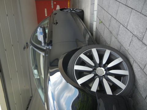 2010 Audi A4 - A black car is shown from the side, distinctive multi-spoke alloy wheels and a reflection of the sky on its body.