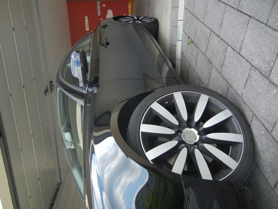Black car side view with multi-spoke alloy wheels