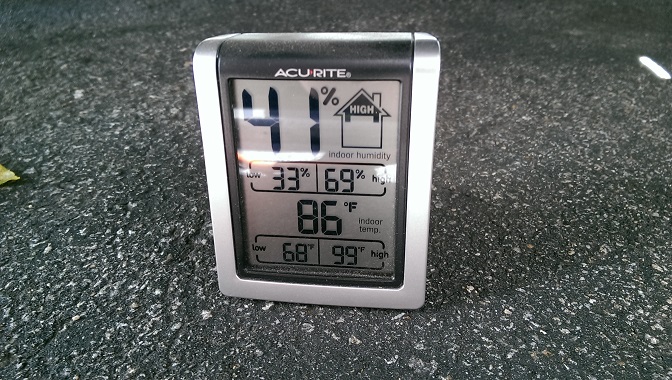 AcuRite indoor thermometer/hygrometer on pavement showing 41% humidity and 86°F