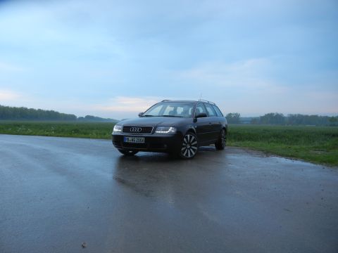 2003 Audi A6 - A dark Audi A6 Avant is parked on a wet road under a cloudy sky.