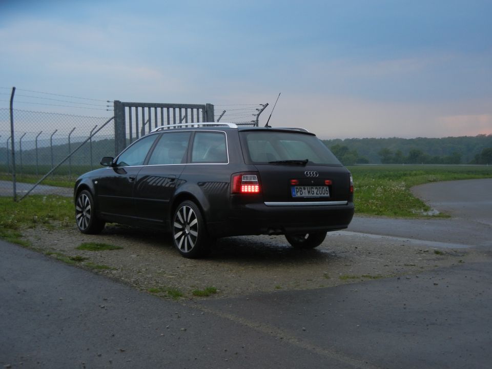 Dark Audi A6 Avant parked near a fence and gate, license plate PB-MG 2006