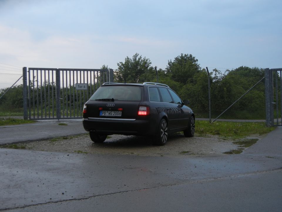 Dark Audi A6 Avant parked near a gate, rear view. License plate reads PB-MS 2006