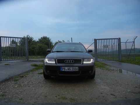 2003 Audi A6 - The Audi A6 Avant is parked in front of a closed gate under a cloudy sky.
